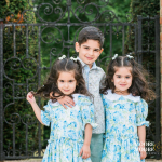 Three siblings standing closely together outdoors, smiling naturally and showing connection and warmth during a relaxed family portrait in Hampshire.