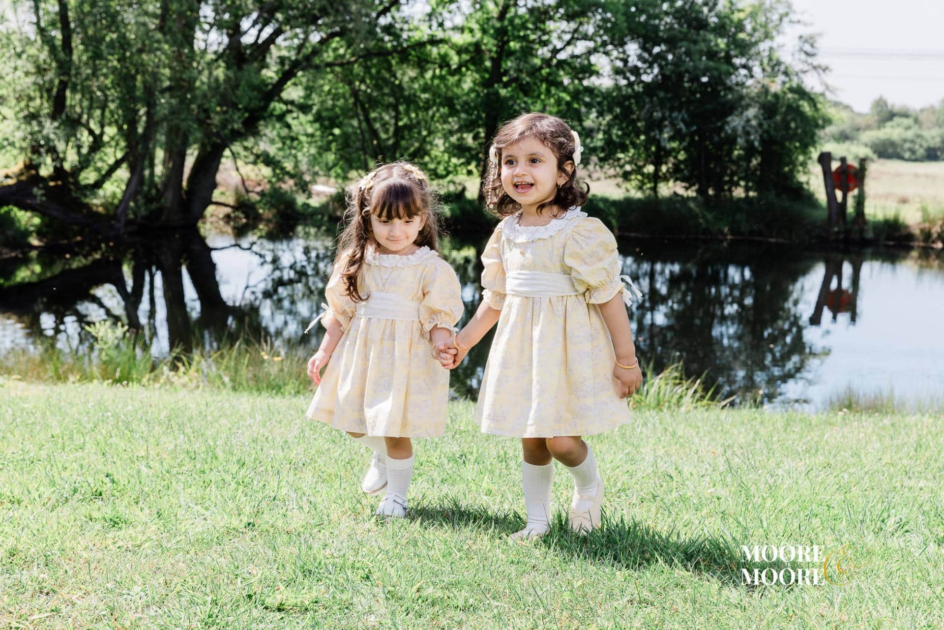 Two young sisters holding hands walking together during a natural family portrait session in Fleet Hampshire