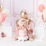 Baby girl enjoying a first birthday cake smash during a calm, play-based photoshoot with a First Birthday photographer in Fleet, Hampshire