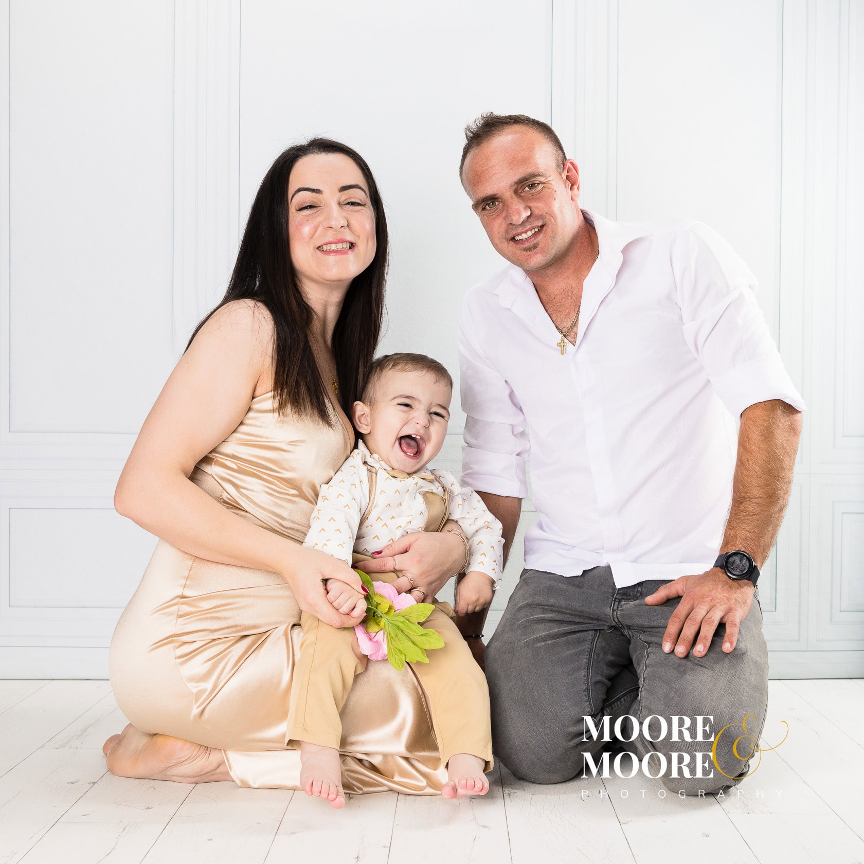 mother-and-father-holding-one-year-old-baby-smiling mother and father holding happy one year old baby during first birthday celebration