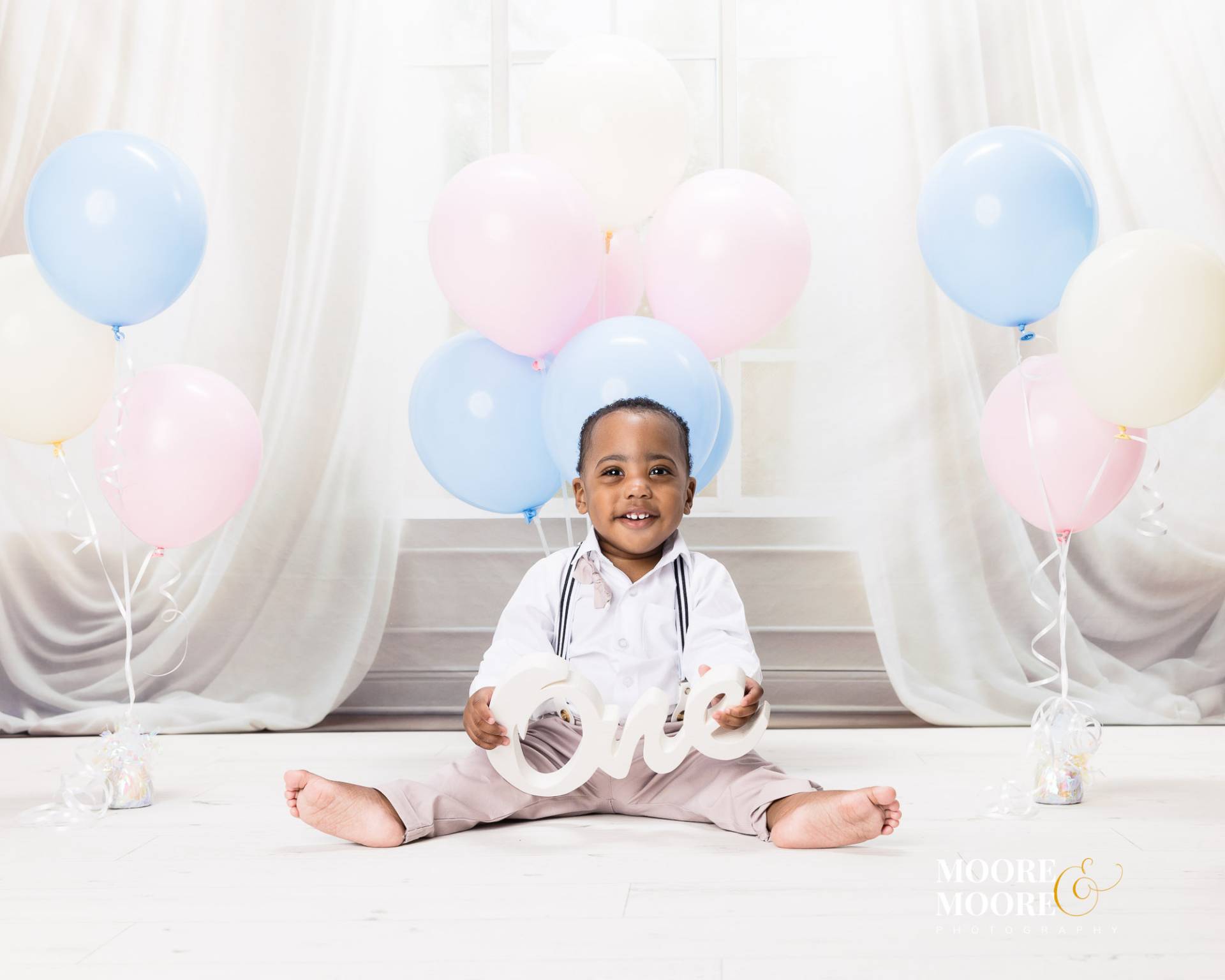 one-year-old-baby-balloons-first-birthday-portrait one year old baby sitting with pastel balloons holding one sign during first birthday portrait